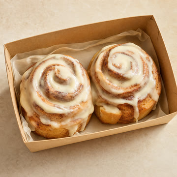 Caja abierta con 2 rolls de canela glaseados.