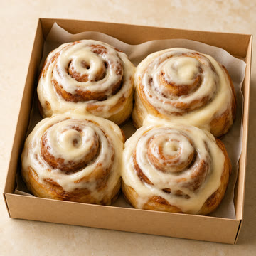 Caja abierta con 4 rolls de canela glaseados.