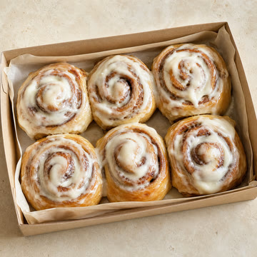 Caja abierta con 6 rolls de canela glaseados.